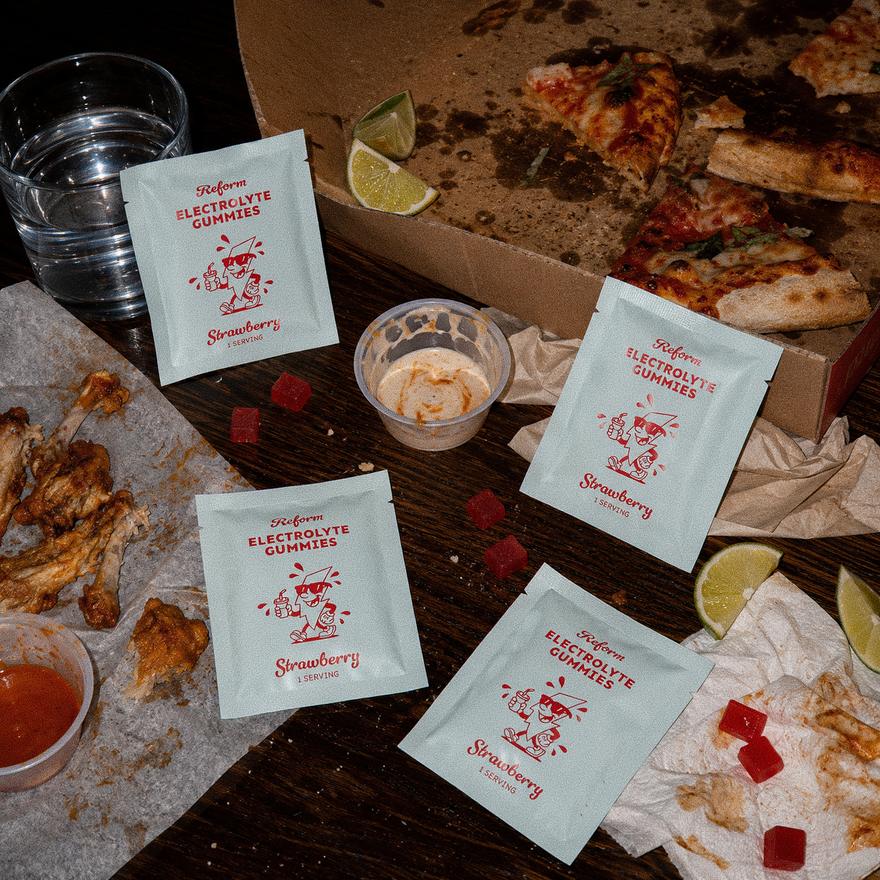 The morning-after table: pizza box, wings, and Reform pouches in the aftermath