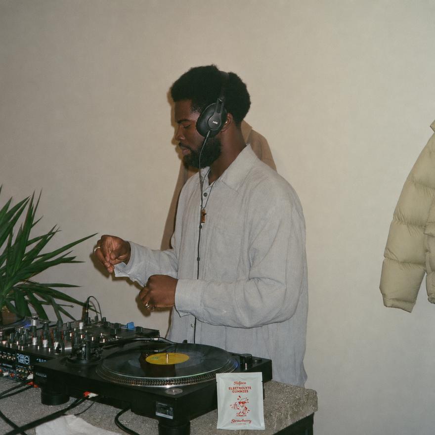 A DJ mid-set with a Reform pouch resting beside the turntable